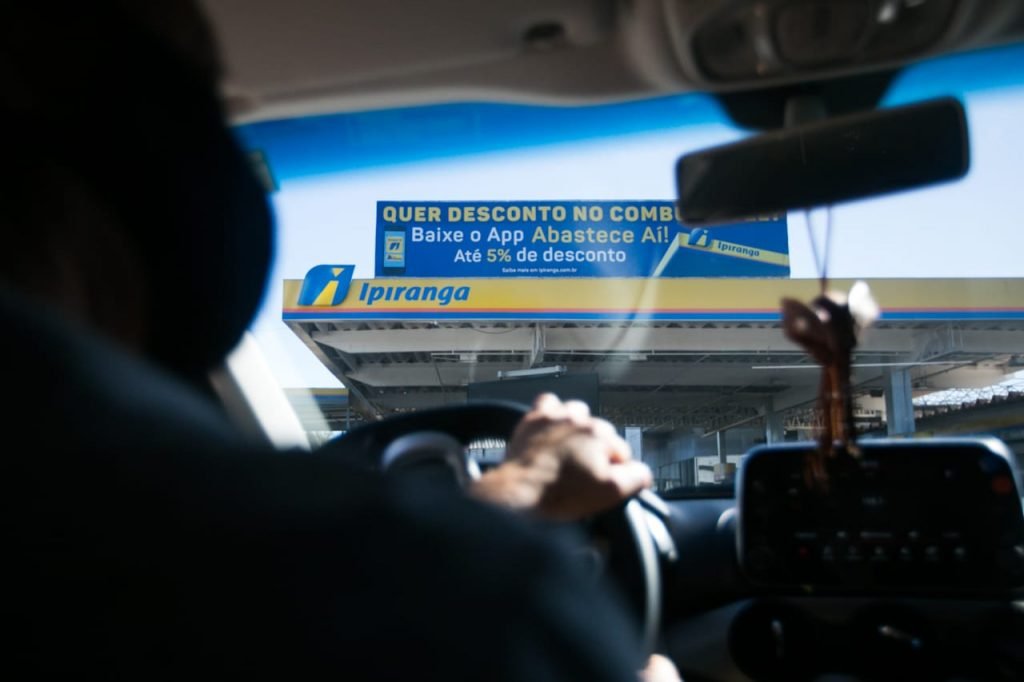 Motorista em frente a posto de combustível