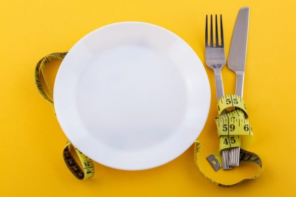 talheres-e-um-prato-branco-com-fita-metrica-em-um-amarelo-o-conceito-de-emagrecimento-e-dieta-alimentar_78492-3736