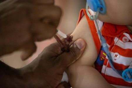 Imagem colorida mostra profissional da Saúde aplicando vacina no braço de uma criança - Metrópoles