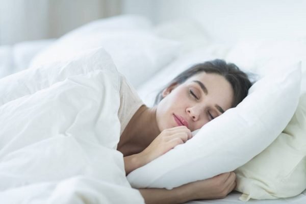 Mulher com travesseiro desfruta de sono de qualidade - Metrópoles