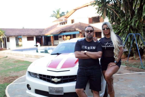 casal em frente a mansão e camaro