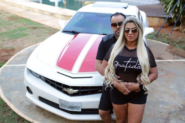 casal em frente a mansão e camaro