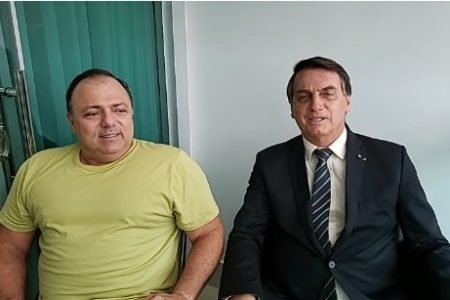Presidente Jair Bolsonaro sentado ao lado de Eduardo Pazuello, em visita ao ministro da Saúde, com Covid-19