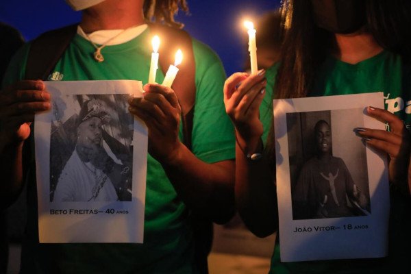 pessoas mostram fotos de homens negros mortos