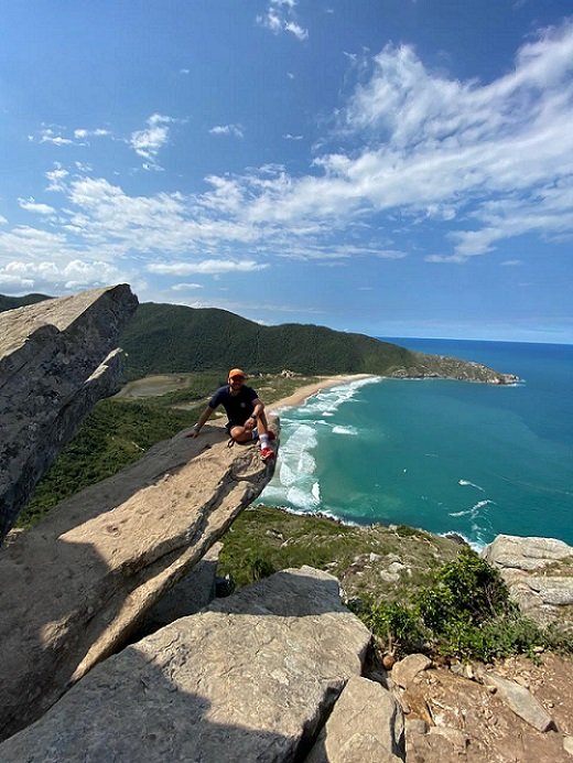 homem sentado em pedra na praia