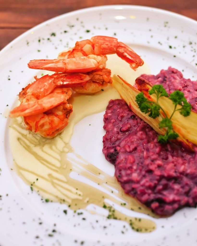 Camarão Laguna, feito com camarões grelhados ao molho de queijo brie com risoto de frutas vermelhas e pesto de manjericão