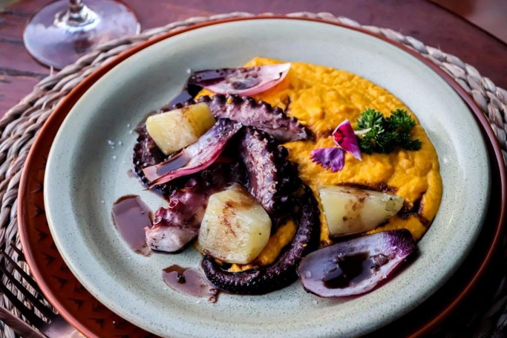 Polvo na parrilla com redução de seu próprio caldo, acompanhado de purê de buriti, batatas e legumes assados na brasa
