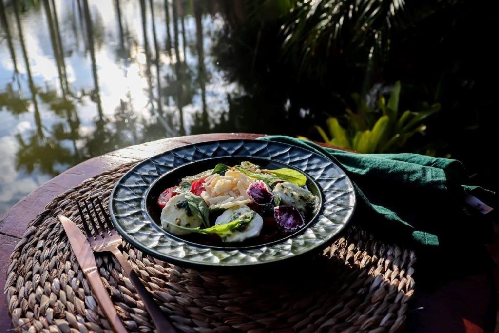 Salada caprese acompanha uma boa variedade de tomates, molho pesto com manjericão, folhas verdes e finalizada com mozarela