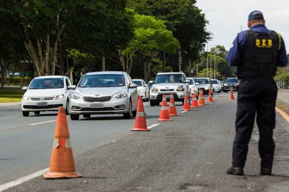 Blitz do DER com agente, cones e carros passando