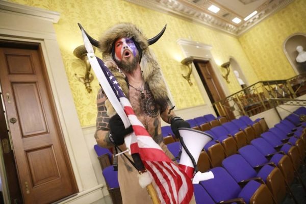 Homem com roupa de chifres segurando bandeira dos EUA