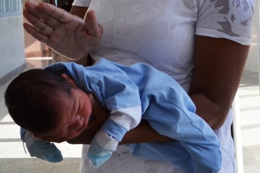 Na foto, uma mulher segurando um bebê de bruços - Metrópoles