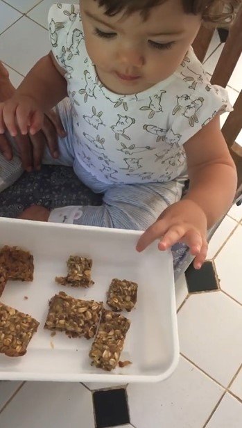 Clara Maria comendo barrinha de cereais