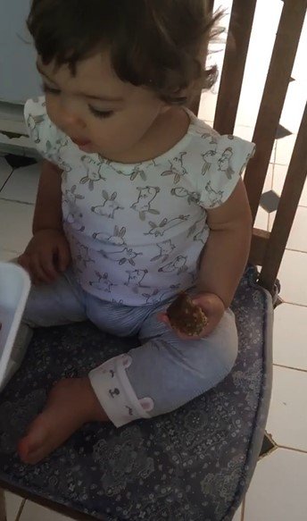 Clara Maria comendo barrinha de cereais