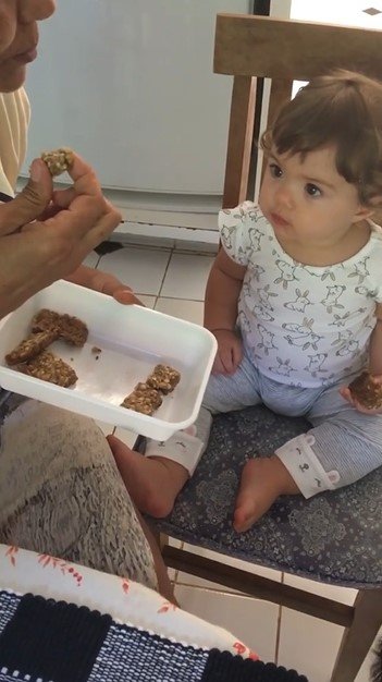 Clara Maria comendo barrinha de cereais