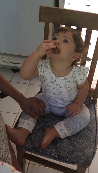 Clara Maria comendo barrinha de cereais
