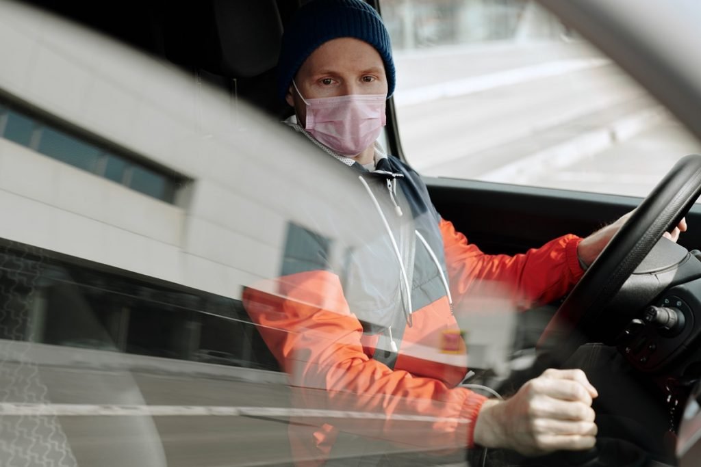 Color photo of man in mask driving car