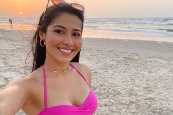 Foto colorida de Thaynara OG. Ela está na praia, de biquíni rosa e sorrindo - Metrópoles