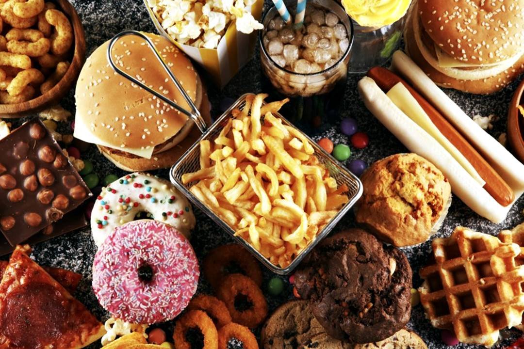 Fotografia mostra vários tipos de alimentos ricos em gordura, como batata frita, cachorro quente e donuts - Metrópoles