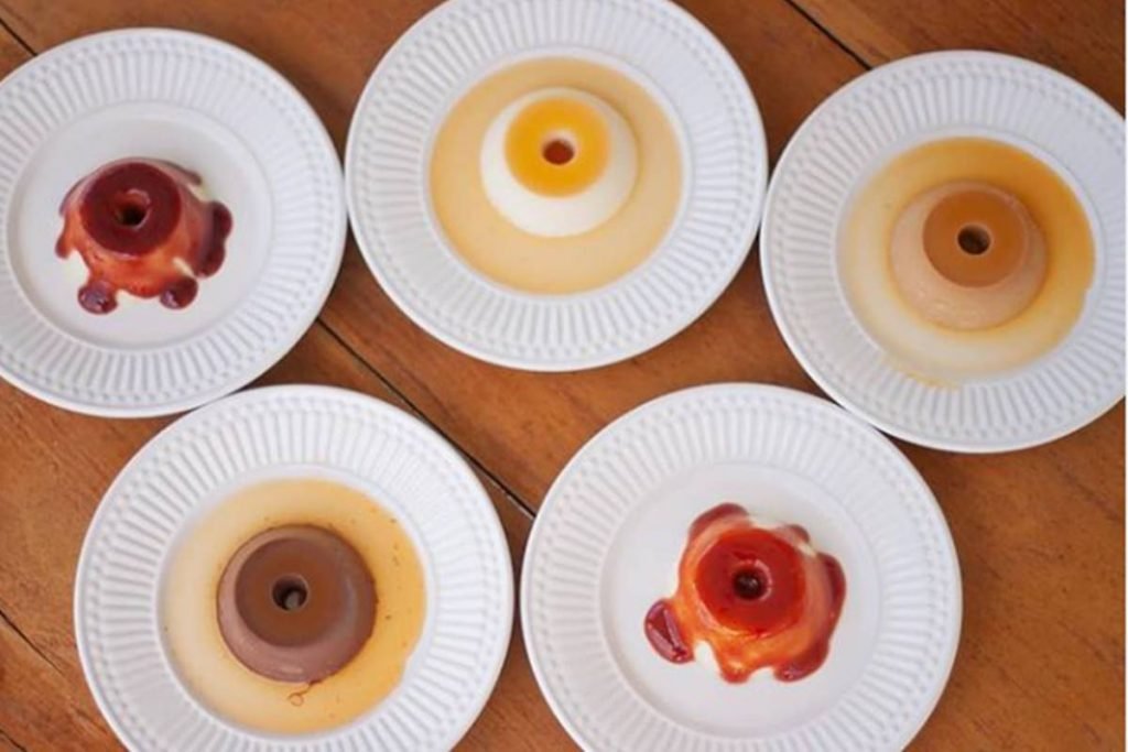 Cinco mini pudins em pratos sobre mesa