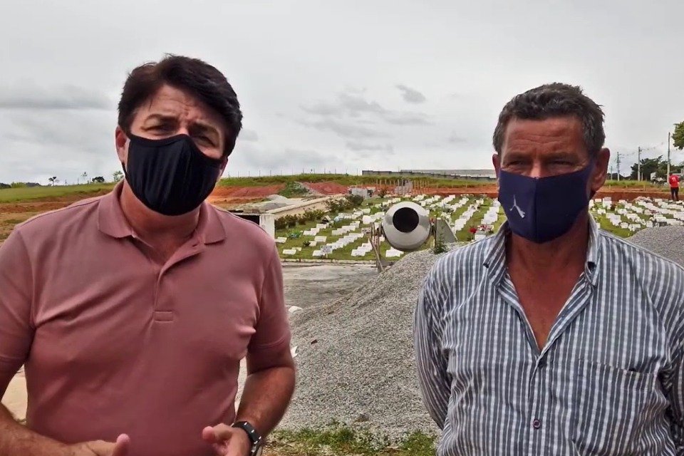 Prefeito Inho, à direita, e Tião, à direita. Ao fundo, o cemitério de Biritiba-Mirim, em obras