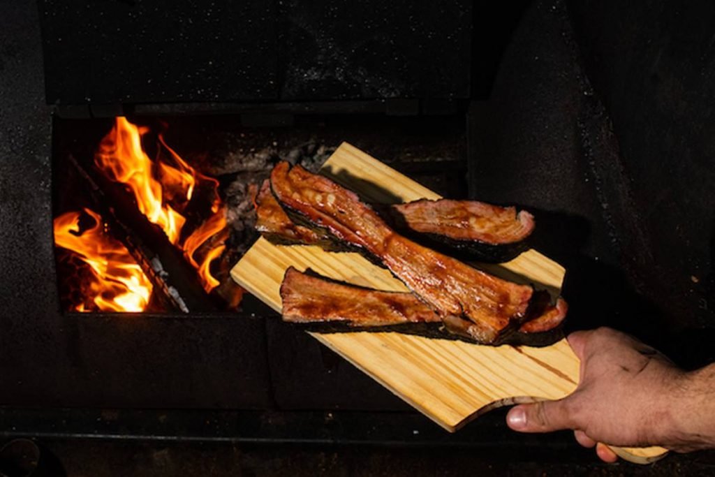 Costelas de porco sobre tábua com fogo de fundo