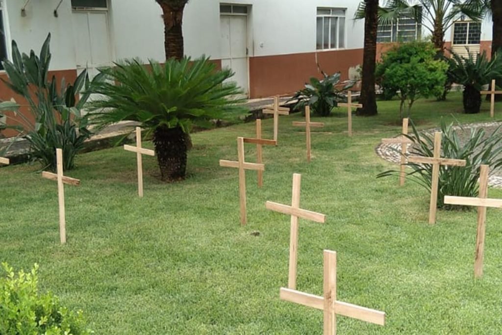Cruzes de madeira no jardim da igreja Cristo Rendentor em Itapuranga, Goiás, expressando luto pelas vidas perdidas na pandemia
