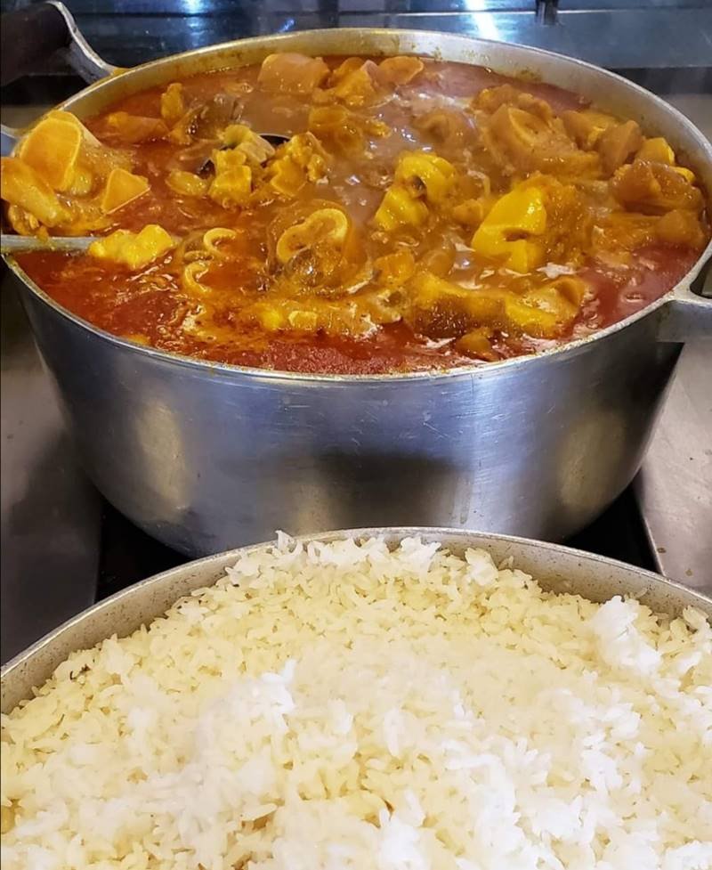 Panela com mocotó ao fundo e panela com arroz na frente