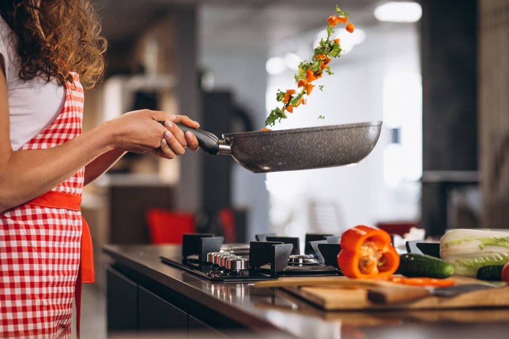 Mulher segura frigideira e joga legumes para o alto