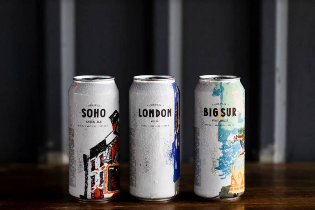 Três latas de cerveja sobre mesa de madeira