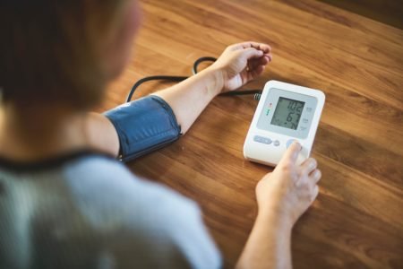 Pessoa aferindo a pressão arterial com aparelho eletrônico - Metrópoles