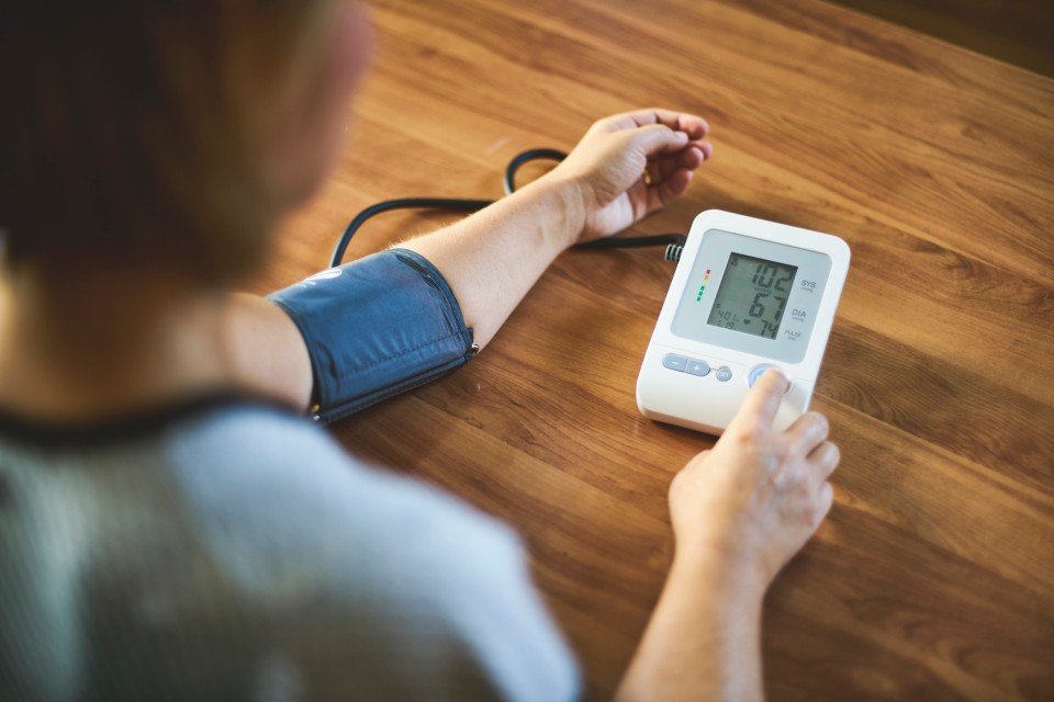 Pessoa aferindo a pressão arterial com aparelho eletrônico - Metrópoles