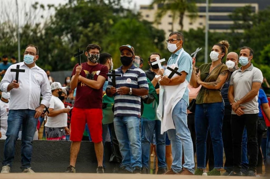 donos e funcionários de bares de goiânia, goiás, em protesto em frente a prefeitura, segurando cruzes e cartazes