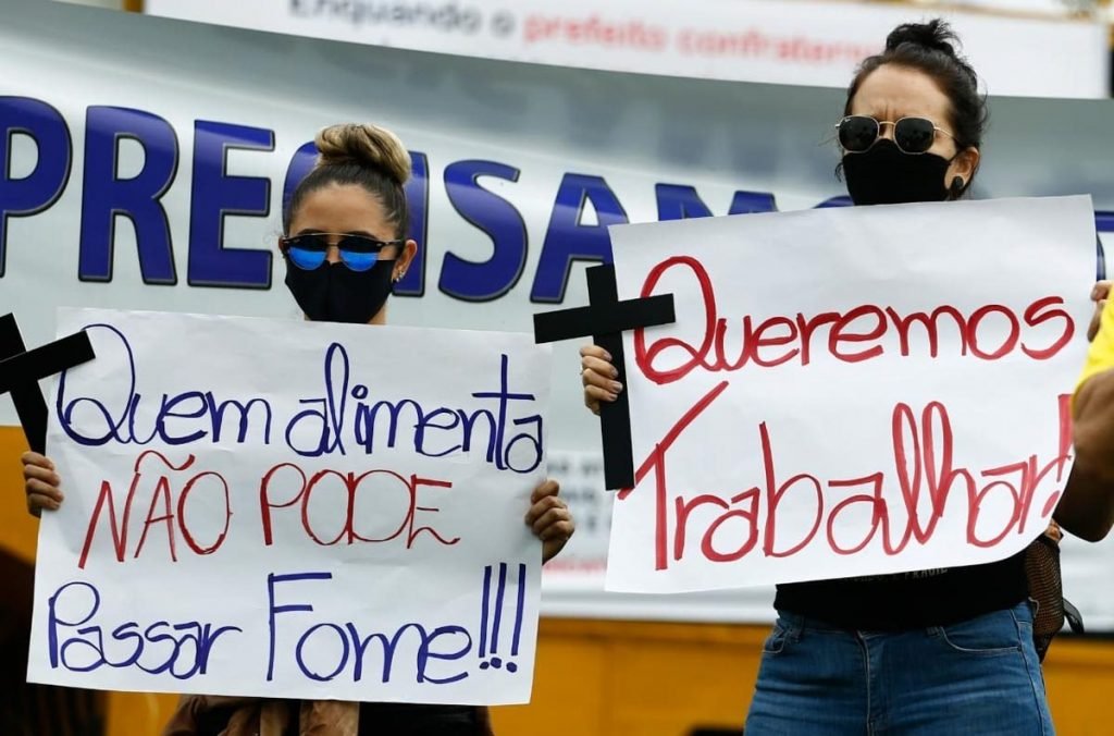 donos e funcionários de bares de goiânia, goiás, em protesto em frente a prefeitura, segurando cruzes e cartazes