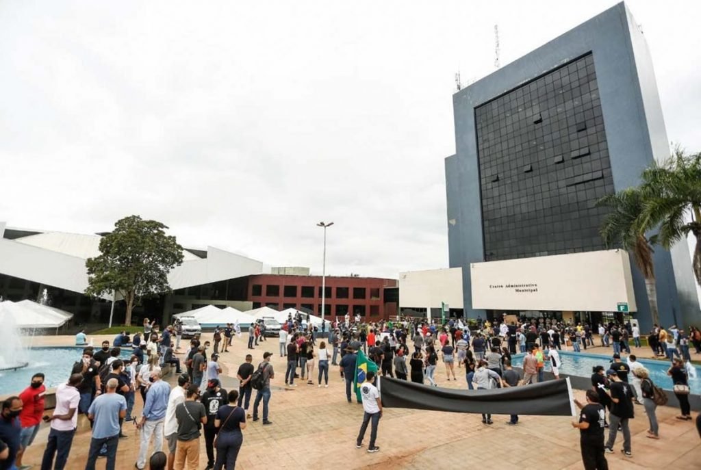 donos e funcionários de bares de goiânia, goiás, em protesto em frente a prefeitura, segurando cruzes e cartazes