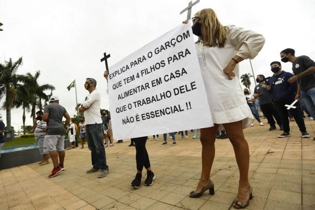 donos e funcionários de bares de goiânia, goiás, em protesto em frente a prefeitura, segurando cruzes e cartazes
