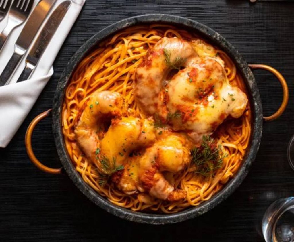Panela rasa com macarrão e camarões a parmegiana por cima