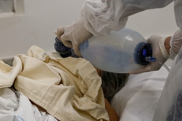 profissional de saúde usa balão de ar manual para auxiliar paciente grave com covid-19 na respiração, em hospital de goiânia