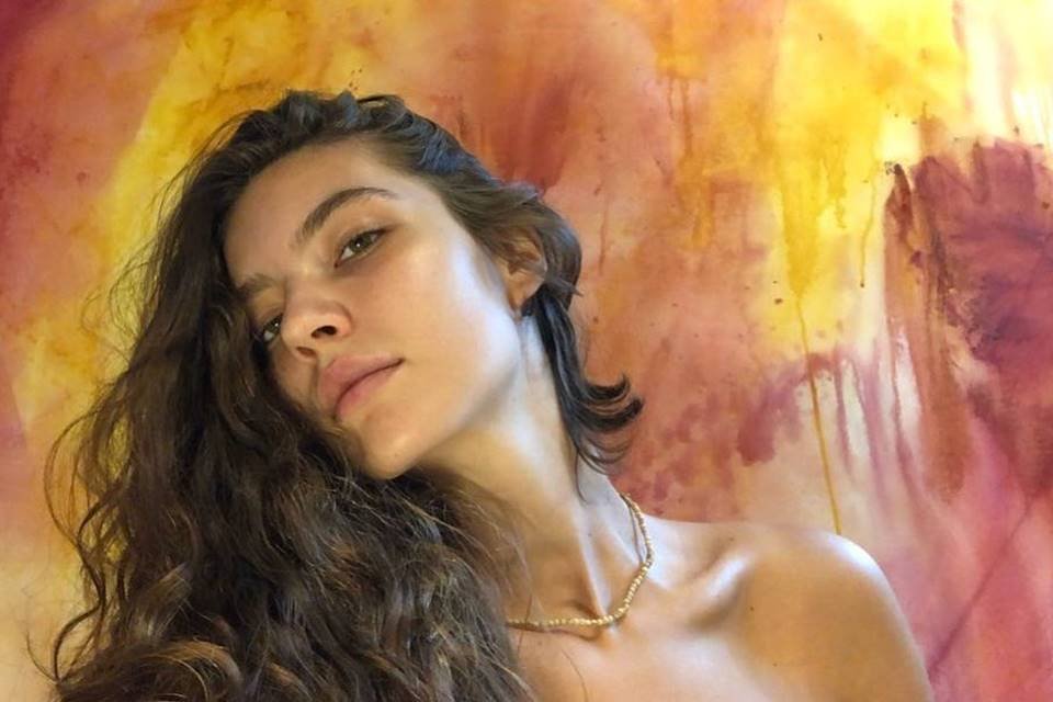 Foto colorida de Alanis Guillen com fundo amarelo e rosa - Metrópoles