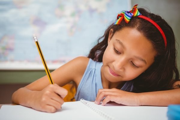 menina com laço vermelho na cabeça escrevendo com lápis em uma caderno