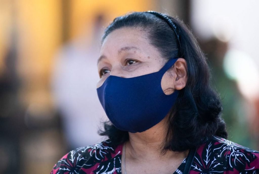 Mulher de máscara azul com rosto triste