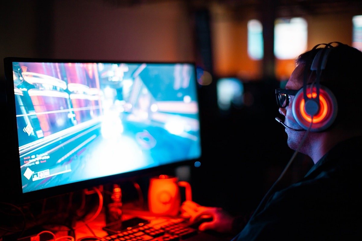Homem de fone olhando para tela de computador enquanto jogo
