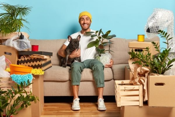 cachorro e homem num sofá rodeados de plantas