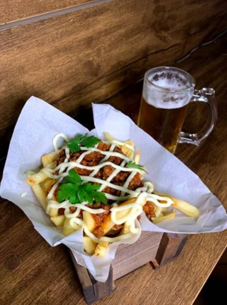 Na foto, batata frita com carne de porco e caneca de cerveja ao lado - Metrópoles