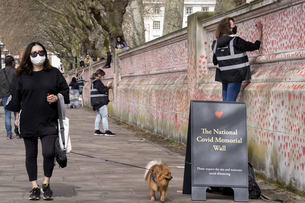 Mulher passeia de máscara ao lado do memorial da covid, em Londres
