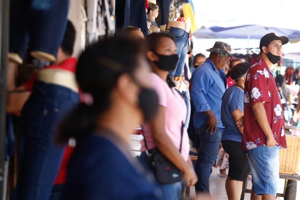 Pessoas de máscara em comércio na rua
