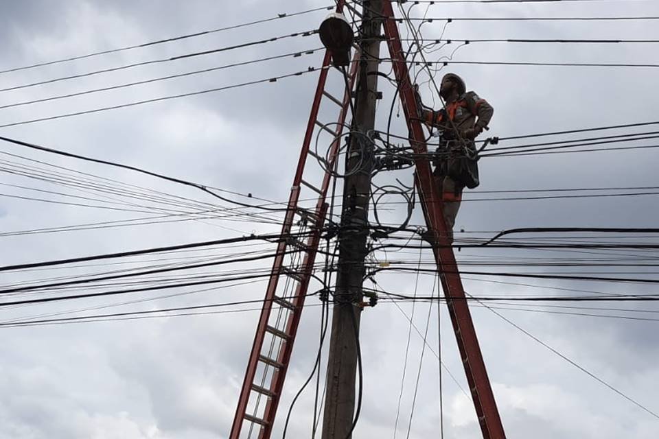 Homem em escada faz manutenção em poste