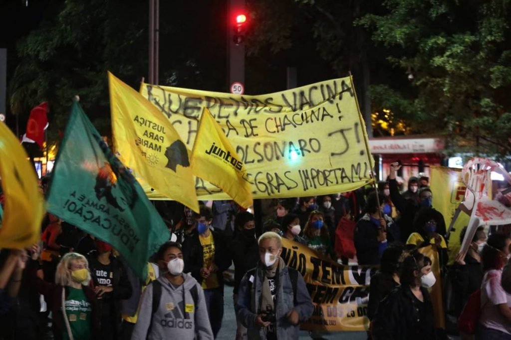 Manifestantes caminham com faixas e bandeiras