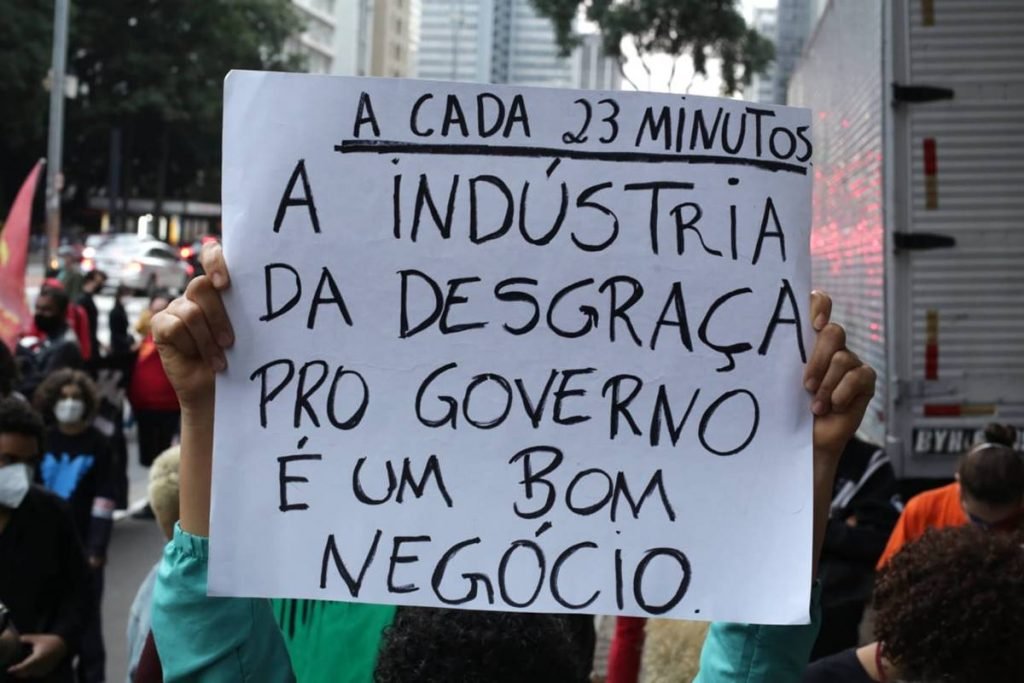 Cartaz com frase A cada 23 minutos a indústria da desgraça pro governo é um bom negócio