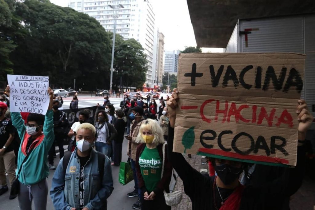 manifestantes e cartaz escrito mais vacina, menos chacina