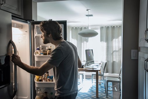 Homem conferindo a geladeira